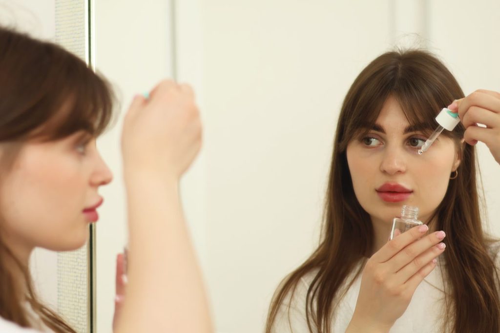 Crafting Captivating Headlines: Your awesome post title goes here A young woman applying skincare serum in front of a mirror indoors. Perfect for beauty and self-care themes.